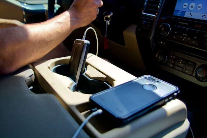 Man Driving Car On Road Trip With Two Phones Charging